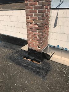 Strategic repairs to built up roofing flashing at chimney in commercial roof in Toronto
