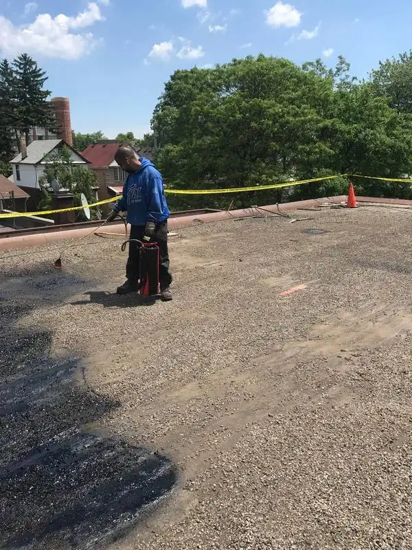 Asphalt primer being applied to tar and gravel commercial roof in Scarborough